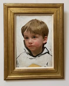 a portrait of a young boy with blue eyes is hanging in a gold frame on the wall