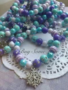 two bracelets with snowflakes and beads on top of a doided doily