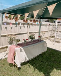 a table with flowers and bunting on it in the backyard under an awning