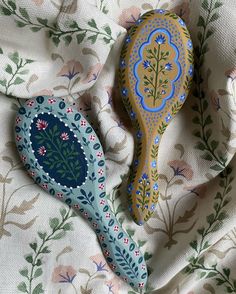 two wooden spoons sitting on top of a floral print table cloth next to each other