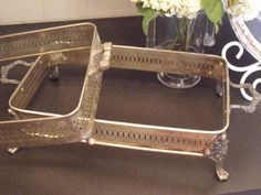 two metal trays sitting on top of a table next to a vase with flowers