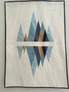 a quilted wall hanging with blue and brown geometric designs on it's sides