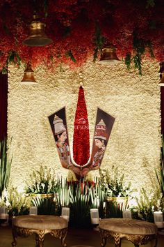 an elaborately decorated stage with red flowers and two benches in front of the stage