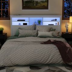 a bed with pillows and blankets on top of it in a bedroom next to two lamps