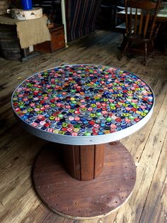 a round table covered in colorful buttons on top of a wooden floor next to chairs