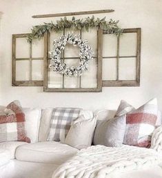 a living room with white couches, pillows and wreaths on the window sill