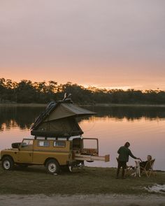 a man standing next to a yellow truck with a camper on it's back