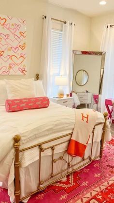 a white bed with pink and orange pillows on top of it next to a mirror