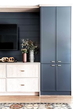 a living room with blue cabinets and a large flat screen tv mounted on the wall