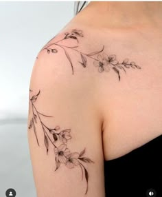 a woman's shoulder with flowers and leaves on her left arm, in black ink