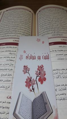 an open book with arabic writing and flowers on the pages is shown in this image