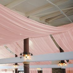 the ceiling is covered with pink draping and hanging lights in front of it