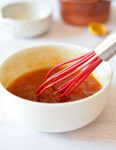 a white bowl filled with sauce and whisk