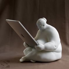 a white statue sitting on top of a laptop computer