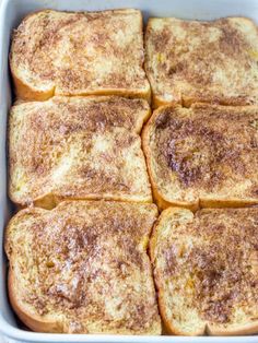 several slices of french toast in a white casserole dish with brown sugar on top