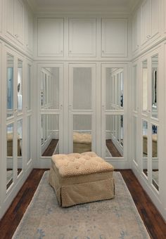 an empty room with white walls and wooden flooring has a footstool on the rug