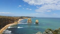 the ocean is clear and blue with waves crashing in front of two large rock formations