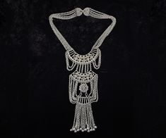 "STUNNING and ultra rare runway necklace by Goldette! Circa 1960s - 1970s, this MASSIVE statement piece features a multi-chain \"waterfall\" design in silver tone metal. The details on this necklace are incredible, from the cutwork, filigree construction to the dangling fringe with silver ball beads. The oversized bib portion (10\" long!) has been articulated for kinetic motion, creating a fluid and sensual look when worn. The necklace measures 22.5\" long, and the ornate closure latches with a secure fold-over clasp. Weighty, substantial, and in excellent condition. This is undoubtedly one of Goldette's largest and most exquisite statement pieces of all time!  MAKER: unsigned Goldette  MATERIAL: silver tone metal PENDANT / BIB: 10\" long x 4\" wide  CHAIN: 22.5\" long WEIGHT: 7 oz / 198 g Runway Necklace, Runway Jewelry, Display Mannequins, Waterfall Design, Egyptian Revival, Gem Necklace, Silver Filigree, Metal Pendant, Cut Work