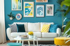 a living room with blue walls and pictures on the wall above the white couches