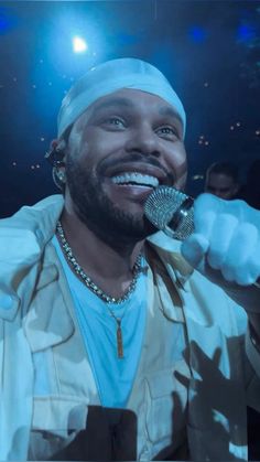 a man with a microphone in his hand and wearing a turban on top of his head