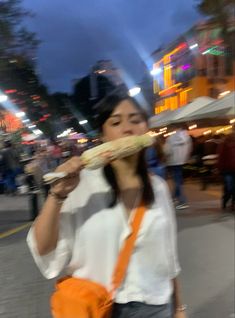 a woman walking down the street while holding a pizza in her hand and eating it