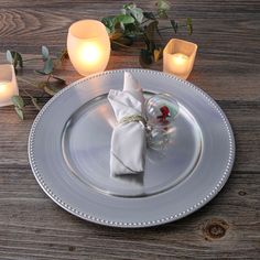 a white plate with a napkin and some candles on the table next to each other