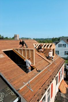 two men are working on the roof of a house that's being built with wood shingles