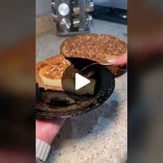 a person holding a piece of pie on top of a black plate in front of a toaster oven