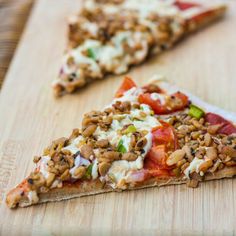 two slices of pizza sitting on top of a wooden cutting board next to each other