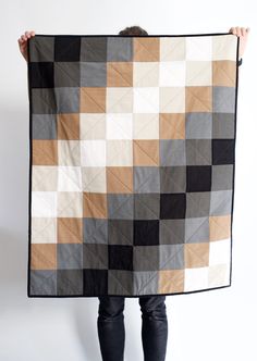 a person holding up a large quilt with different colors and shapes on it's sides