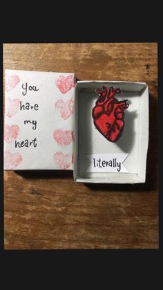 an open box with a red heart in it on a wooden table next to a piece of paper that says you have my heart