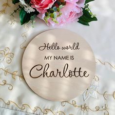 a wooden sign that says hello world, my name is charlotte next to some flowers