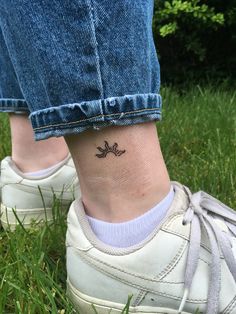 a woman's foot with a small tattoo on her left ankle, in the grass