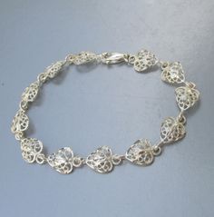 "This very pretty 1980s sterling silver bracelet has twelve lacy filigree heart shaped links.  It is marked 925 for sterling on the lobster claw clasp, and it measures 7 1/2\" long and almost 1/2\" wide.  It is in mint, like-new condition with no sign of any wear and was freshly hand-polished.    FREE SHIPPING within the USA and it will arrive gift boxed.    0523" Silver Metal Heart Bracelet For Wedding, Silver Heart-shaped Chain Bracelet For Wedding, Engraved Silver Heart Bracelet For Wedding, Heart-shaped Sterling Silver Bracelet For Weddings, Filigree Heart, Filigree Jewelry, Vintage Cameo, Sterling Silver Bracelet, Chain Link Bracelet