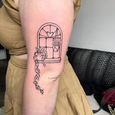 a woman with a tattoo on her arm has a bird in a window and vines