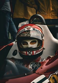 a man sitting in a racing car wearing a helmet