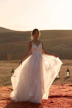 a woman in a wedding dress standing on a hill