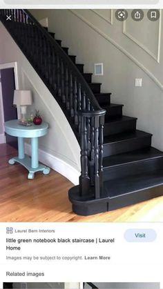 there is a black stair case next to the table and lamp on the floor in this room