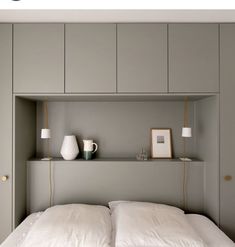 a bed with white sheets and pillows in a room that has built - in shelving