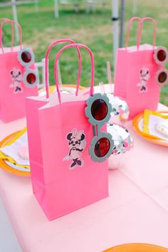 pink paper bags with mickey mouse on them are sitting on a table in the grass