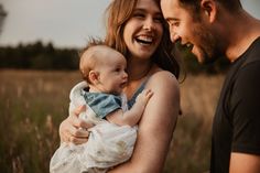 a man and woman holding a baby in a field