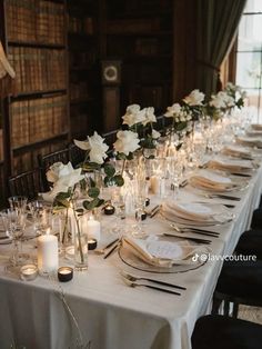 a long table is set up with white flowers and candles for an elegant wedding reception