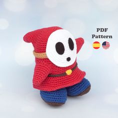 a crocheted stuffed animal wearing a red coat and blue pants, with an eye patch