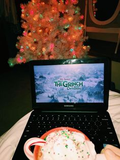 a laptop computer sitting on top of a table next to a cup of hot chocolate