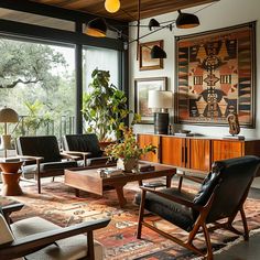 a living room filled with lots of furniture and large windows overlooking the trees in the distance