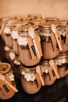 there are many mason jars with spoons and tags in them on top of the table