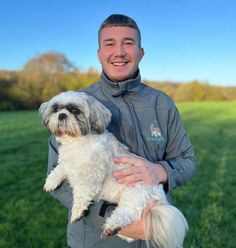 a man holding a small white dog in his arms