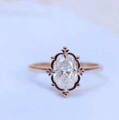 a close up of a ring on a white surface with an oval shaped diamond in the center