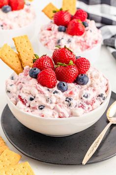 a bowl of fruit dip with crackers and strawberries on the side, ready to be eaten