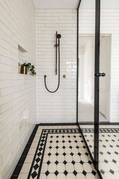 a black and white tiled bathroom with a shower head in the corner next to it